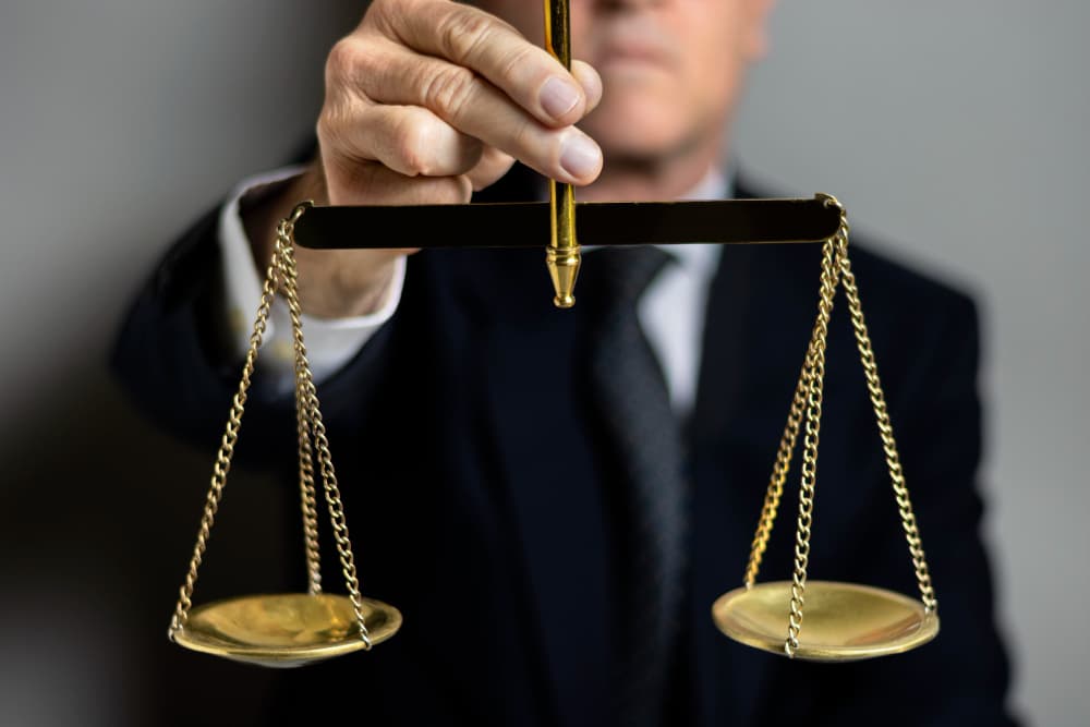 A person in a suit holding a set of brass scales of justice